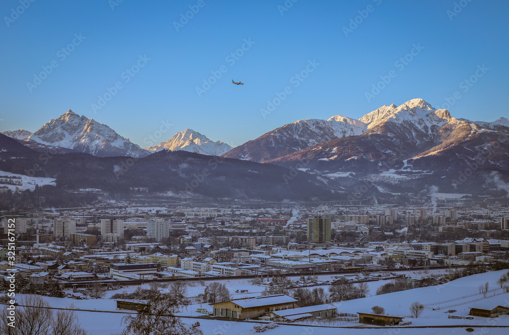 airplane over the city.Mountains in the background