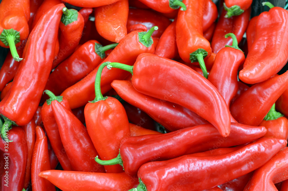 Red hot chilly peppers in a pile for sale - many red peppers background