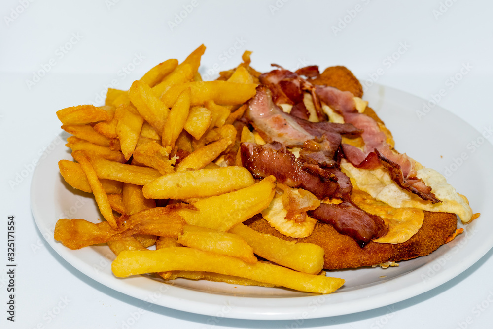 Argentinian food. Milanesa with bacon and cheese with french fries Argentinian food. Milanesa with bacon and cheese with french fries