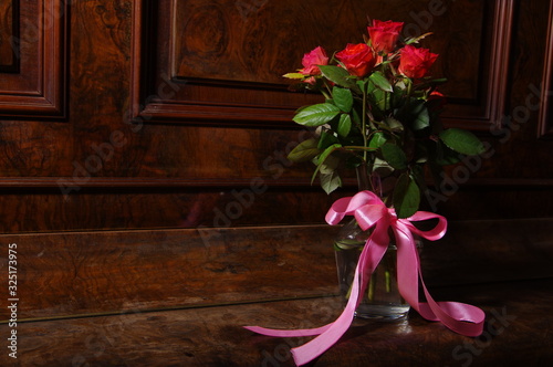 Red roses bouqet on the vintage old wooden piano