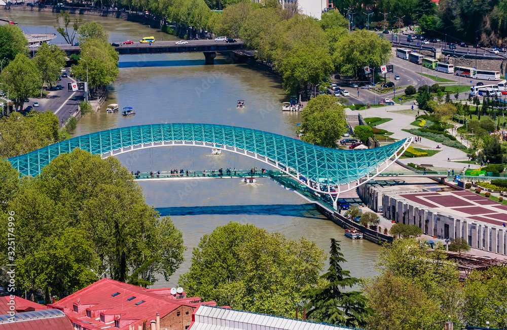 Fototapeta premium View Of Kura Mtkvari River Under Bridge Of Peace And Baratashvili Bridge, Embankment And City Neighborhood, Tbilisi, Georgia