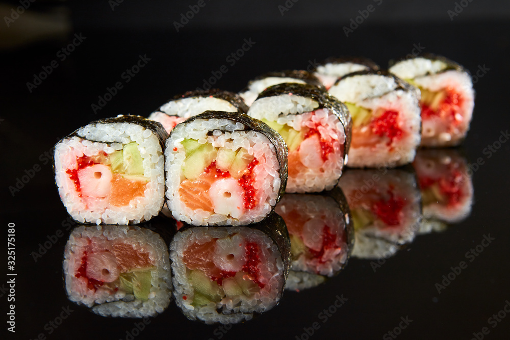Traditional sushi roll with salmon, cream cheese, shrimp and cucumber on black stone. Japanese food Traditional sushi roll with salmon, cream cheese, shrimp and cucumber on black stone. Japanese food
