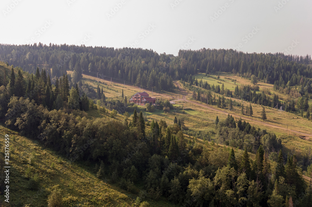 Suburb and villages. Big mountains and green forests. Trees and their shadows on the grass. Summer day with calm deep blue sky and huge clouds around. Fields. Fresh air.  landscape