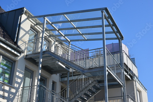 Stahl-Außentreppe mit Glasdach an einem Mehrfamilienhaus