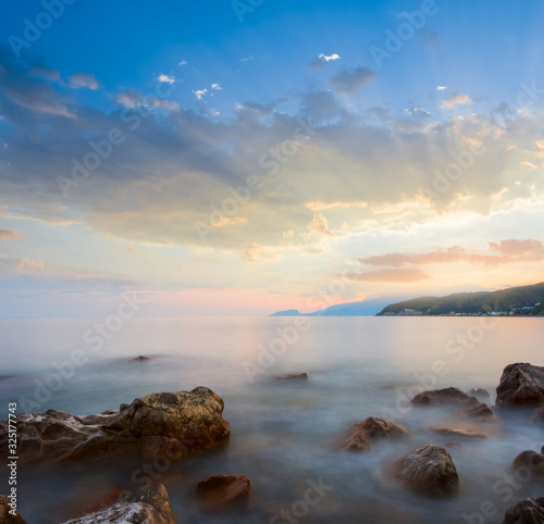 quiet sea bay with stones near a coast at the sunset, vacation outdoor scene