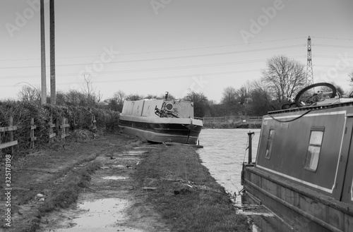 Narrow boat left stranded on a canal bank after floodwater recedes