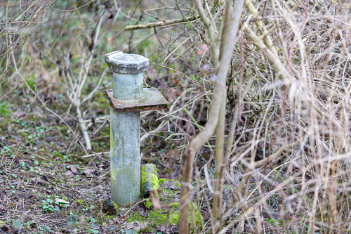 old groundwater observation well in the bushes with moss