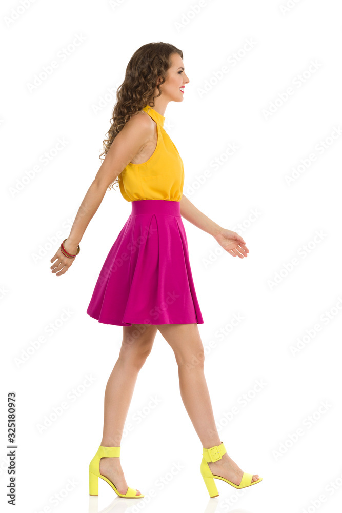 Walking Young Woman Is In Vibrant Clothes And High Heels. Side View. Walking Young Woman Is In Vibrant Clothes And High Heels. Side View.