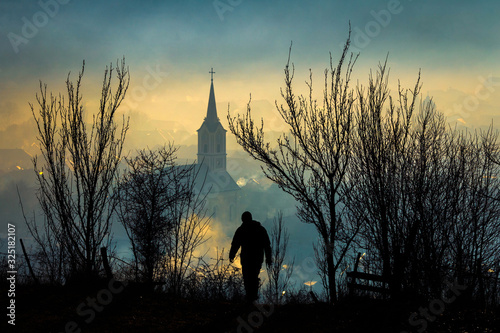 Man silhouette walking towards misty village landscape seen from above