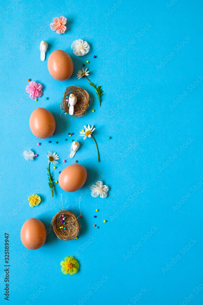 Easter pattern of Eggs with flowers, nests and candies on the blue background. Easter concept. Healthy feeding concept. 
