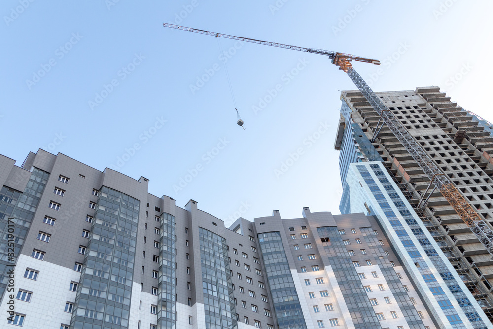 Fototapeta premium Multi-storey building, sunrise, construction crane, blue sky