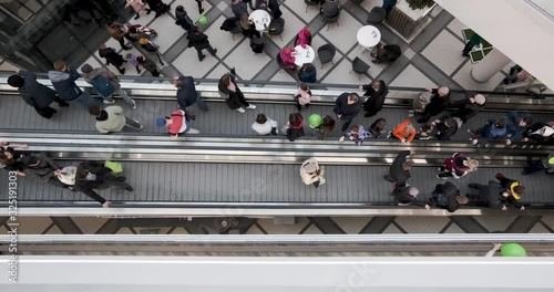 crowd of people on an escalator in a large multi-storey layered shopping center. view from above