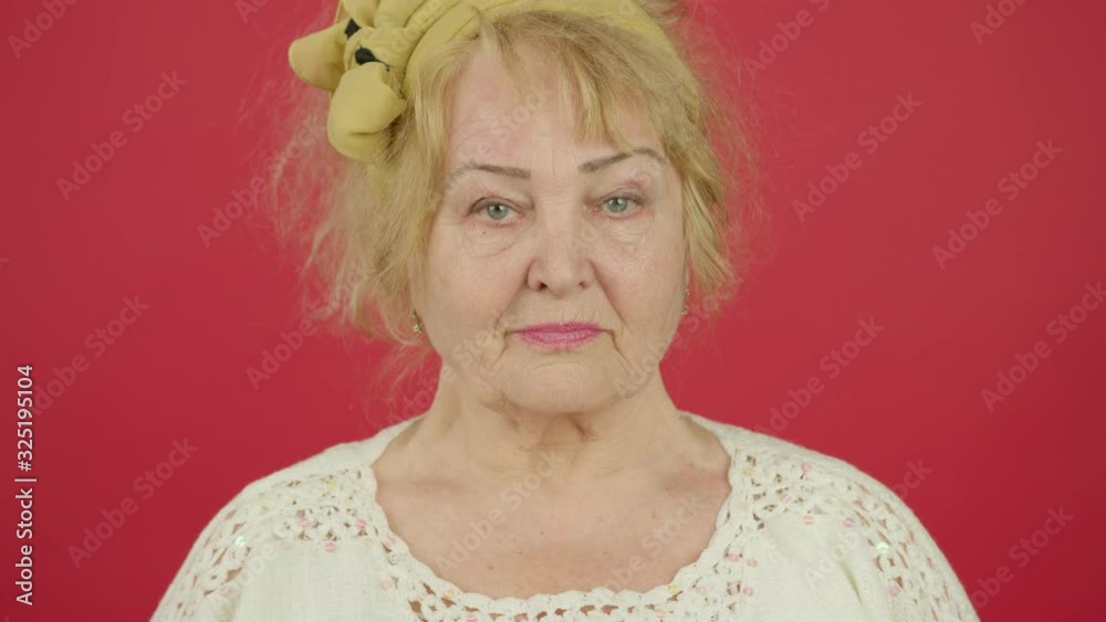 Front view of senior woman looking at camera and shaking head with smile Front view of senior woman looking at camera and shaking head with smile