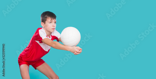 Boy playing volleyball isolated in blue. Physical, sport