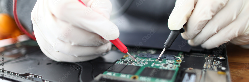 Close-up of male professional working with instruments and tools. Technician wearing protective gloves fixing personal computer circuit board. Gadgets support and maintenance