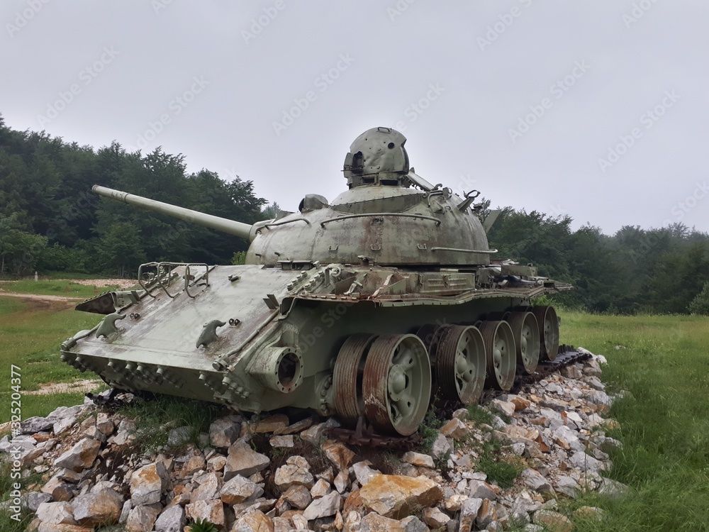 Old soviet tank T-55 from Bosnian war placed on the meadow as a monument