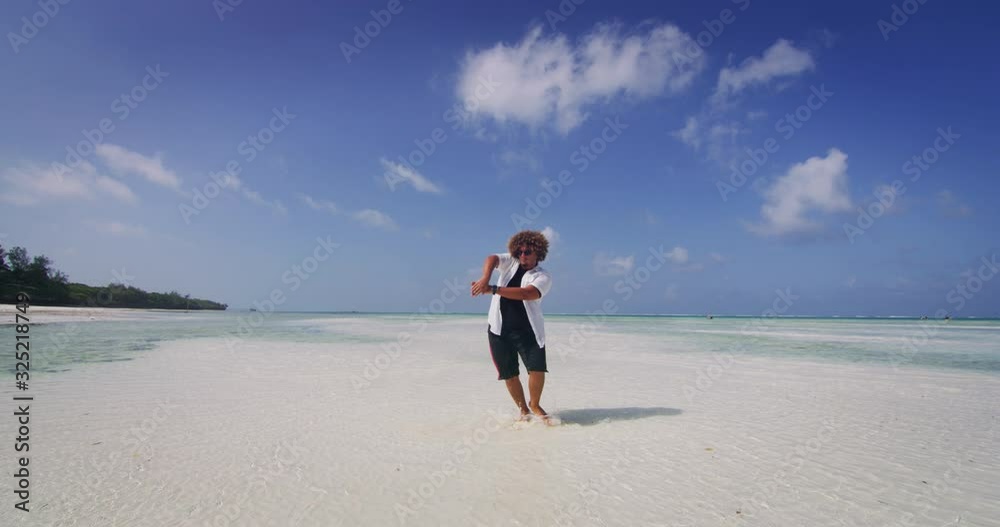 Aerial shot of happy young overweight man is having fun to dancing on a desert beach with clear transparent sea water of a tropical island. Concept of lifestyle, happiness, youth, vacation, holidays Aerial shot of happy young overweight man is having fun to dancing on a desert beach with clear transparent sea water of a tropical island. Concept of lifestyle, happiness, youth, vacation, holidays