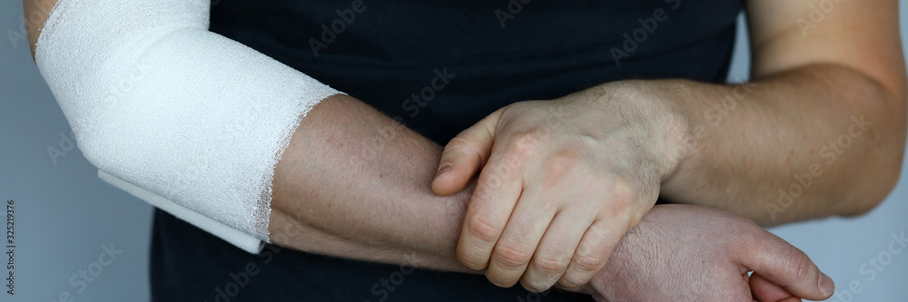 Male hand with tight elastic bandage on elbow closeup. Self help sprain concept Male hand with tight elastic bandage on elbow closeup. Self help sprain concept