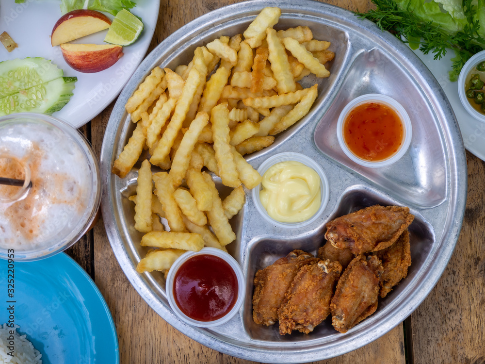 The fried chicken drumstick and french fries on wooden background. The fried chicken drumstick and french fries on wooden background.