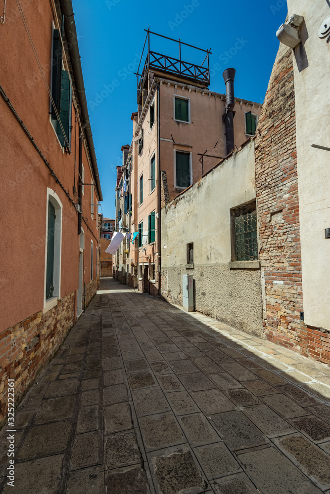 Obraz premium VENICE, ITALY - August 03, 2019: One of the thousands of lovely cozy corners in Venice on a clear sunny day. Locals and tourists strolling along the streets and historical buildings