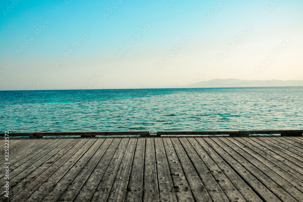 gray wooden deck of pier and blue summer sea with sky