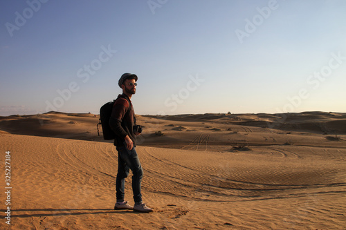 Explorer man with hat and backpack taking pictures in the desert