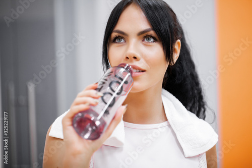 Young beautiful woman in sportswear drinking water.