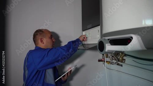 Worker with tablet computer set up central gas heating boiler at home