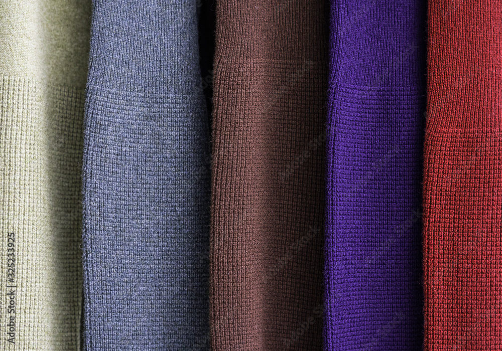 Rack of colourful thick woollen jumpers in a row showing the sleeves. Rack of colourful thick woollen jumpers in a row showing the sleeves.
