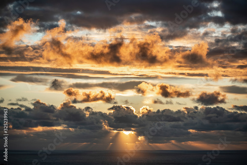 Aerial view of beautiful clouds over horizon with sun rays before sunset