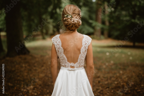 Quadro em tela Bride in park facing back in white wedding dress with lace and bare back