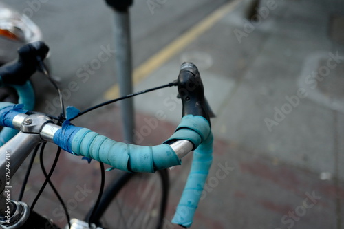 Parked bicycle closeup of handle bars that are light blue