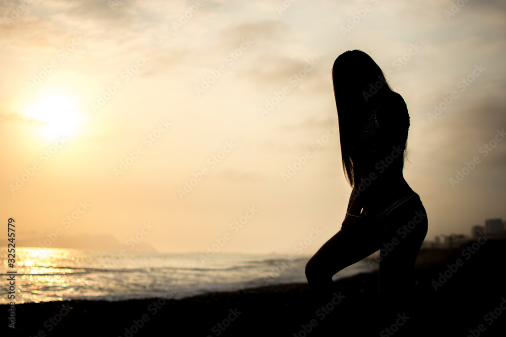 silhouette of young woman on the beach at sunset