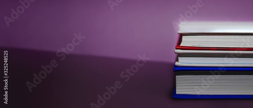 Banner for book advertising. stack hardcover books in blue and white with white sheets on a background of purple color