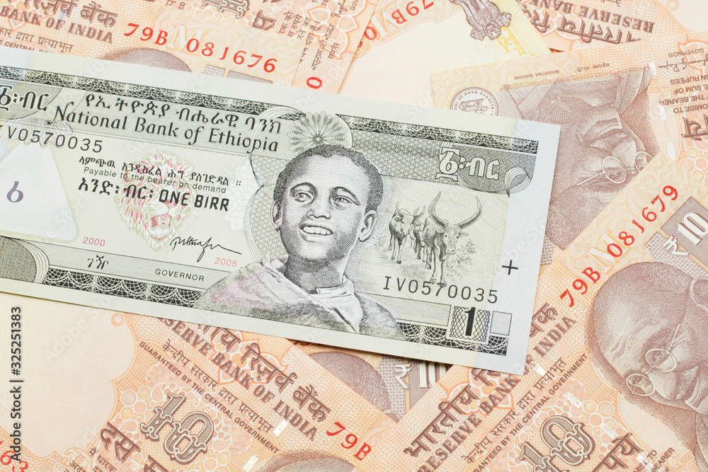 A close up image of a one Ethiopian birr bank note on a background of Indian ten rupee bank notes