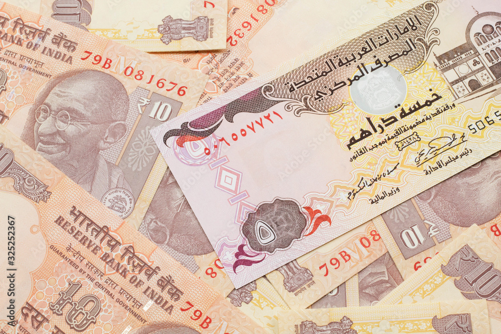 A close up image of a five dirham bank note from the United Arab Emirates on a background of Indian ten rupee bank notes in macro