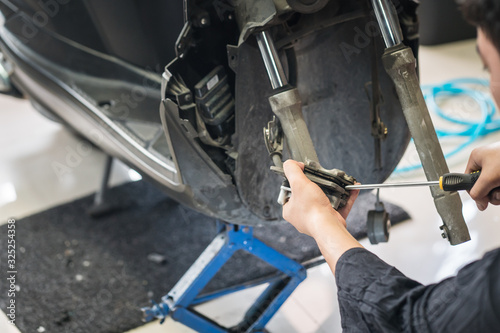 motorcycle mechanic hands replace brakes in garage. Worker changing brake disc. Brake disc installation concept.