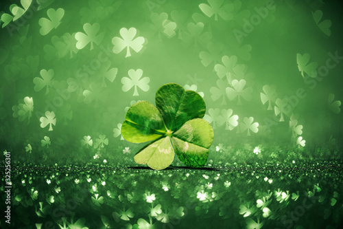 Lucky four leaf clover surrounded by sparkling shamrock shapes photo