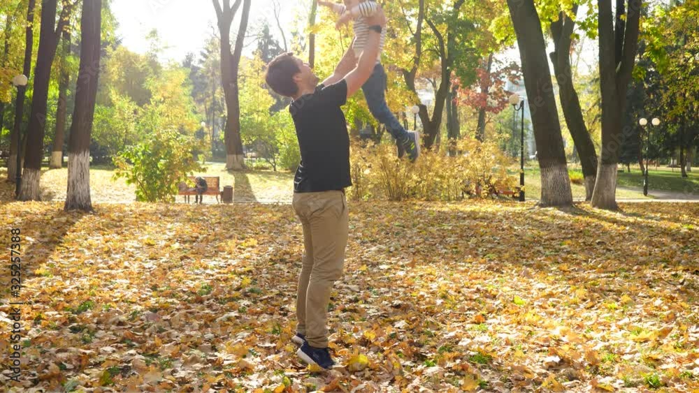 4k video of young father lifting his little son and throwing up in air at autumn park 4k video of young father lifting his little son and throwing up in air at autumn park