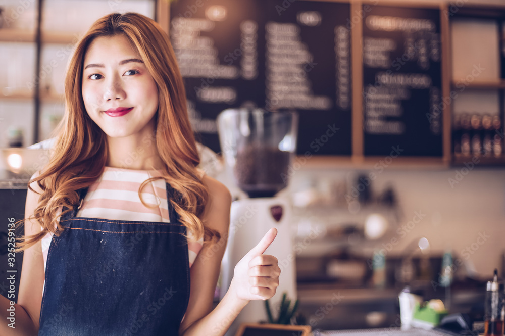 Portrait young Asian woman barista feeling happy smiling at urban cafe. Small business owner Korean girl in apron relax toothy smile