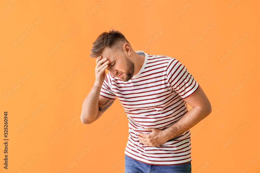Young man suffering from abdominal pain on color background Young man suffering from abdominal pain on color background