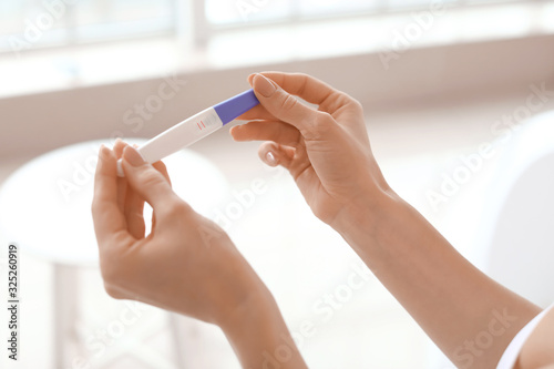 Young woman with pregnancy test in bathroom, closeup