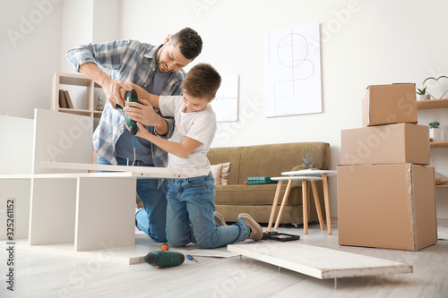 Father and his little son assembling furniture at home photo