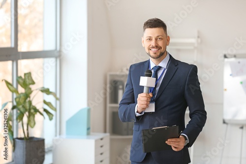 Male journalist with microphone indoors