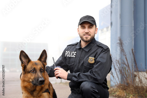 Photo Male police officer with dog patrolling city street