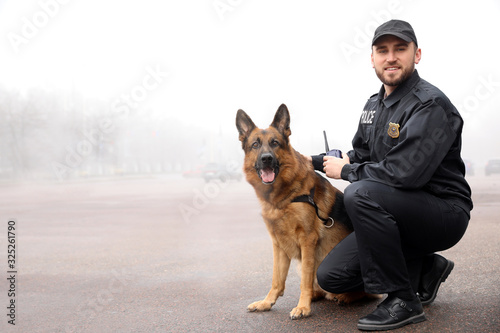 Foto Male police officer with dog patrolling city street