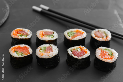 Plate with tasty sushi rolls on table