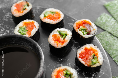 Tasty sushi rolls and soy sauce on table