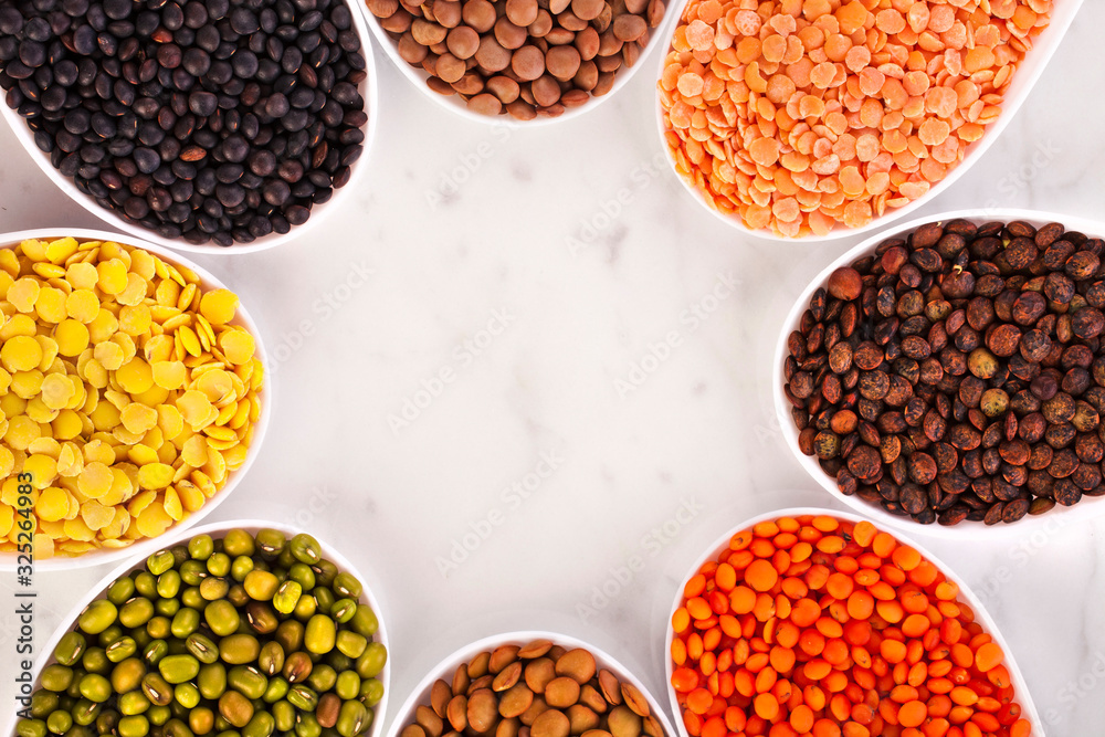 Bowls of various lentils in the shape of flower on a marble background.