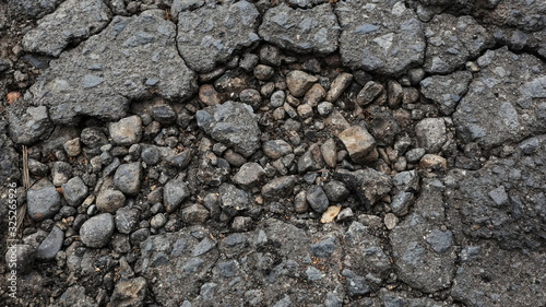 Damaged asphalt road, cracked cracks and scattered stones, with selective focus
